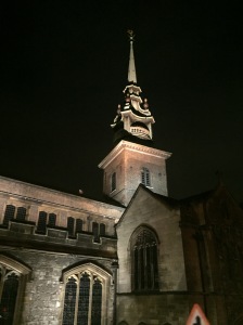 The spire of a church lit from below in sharp contrast to the night sky