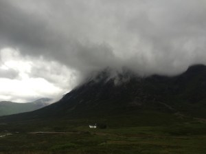 One white house sits at the base of a mountain where mist can be seen forming