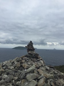 A stone cairn on a small peninsula near the ocean with islands visible in the background