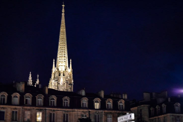 The spire of a cathedral in Bordeau illuminated at night