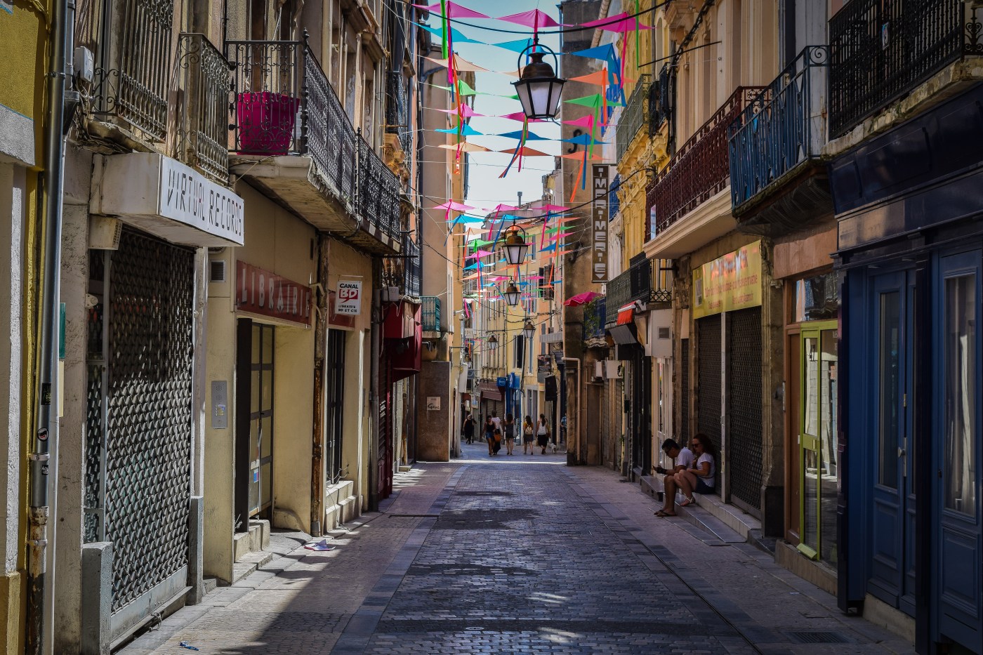 A narrow street lined shop in Narbonne covered with colorful kites