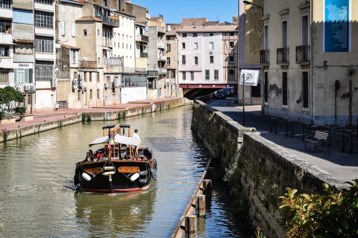 A boat on the Canal de la Robine with the Pont des Marchands in the background