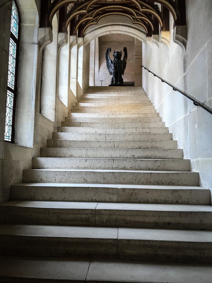 A stairwell inside the Chateau de Pierrefonds leading up to a statue of a griffin.