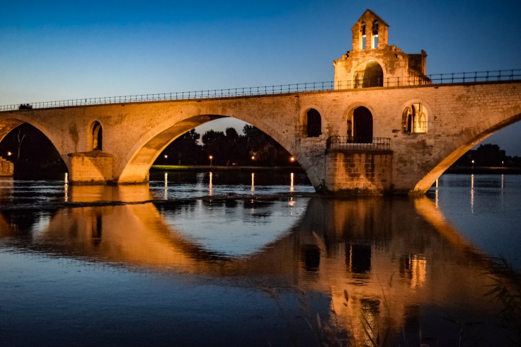 The Pont d'Avignon illuminated over the Rhone at dusk