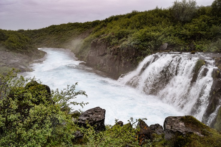 Blue water tumbles over the falls at Midfoss in Iceland